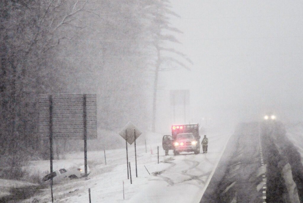 An ambulance crew checks on a vehicle off the road on the northbound side of the Maine Turnpike in Saco during Thursday's snowfall.